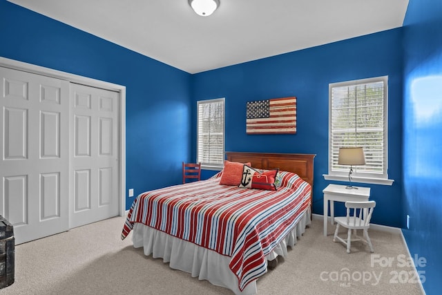 carpeted bedroom with a closet and baseboards