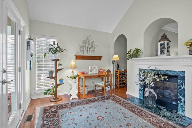 interior space with wood finished floors, visible vents, baseboards, lofted ceiling, and a high end fireplace