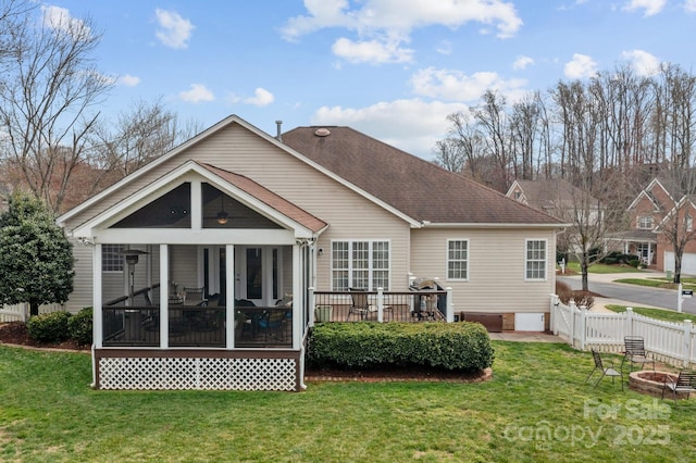 back of house with a lawn, fence, an outdoor fire pit, roof with shingles, and a sunroom