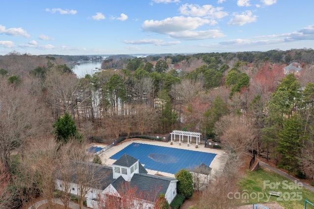 view of swimming pool with a wooded view, a patio area, a water view, and a pergola