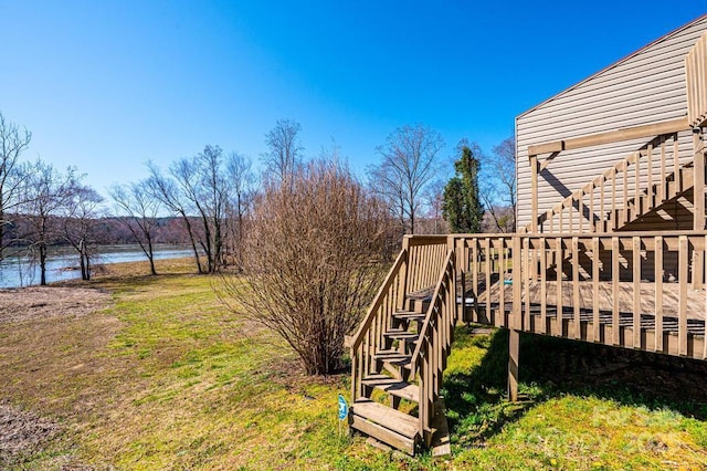 view of yard featuring stairway and a deck with water view