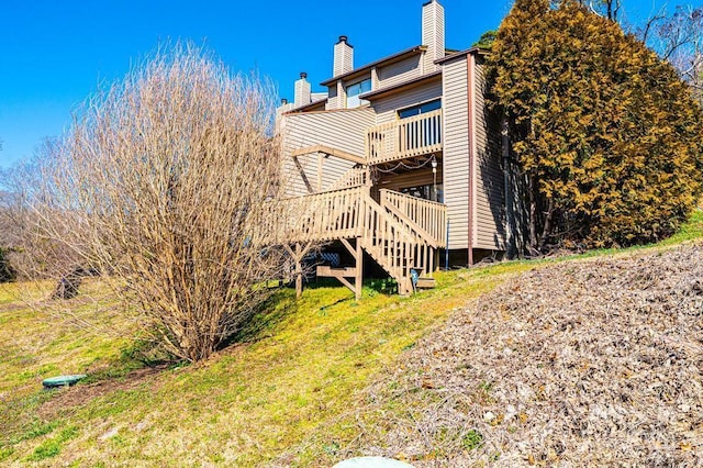 back of property with stairs, a wooden deck, and a chimney