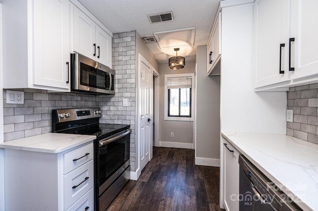 kitchen with visible vents, dark wood-type flooring, light stone counters, white cabinetry, and appliances with stainless steel finishes