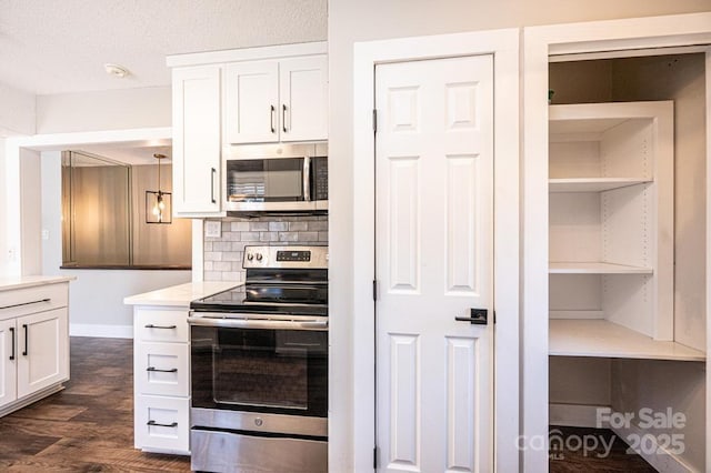 kitchen featuring stainless steel appliances, white cabinets, light countertops, decorative backsplash, and dark wood-style flooring