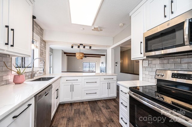 kitchen featuring dark wood finished floors, a peninsula, white cabinets, stainless steel appliances, and a sink