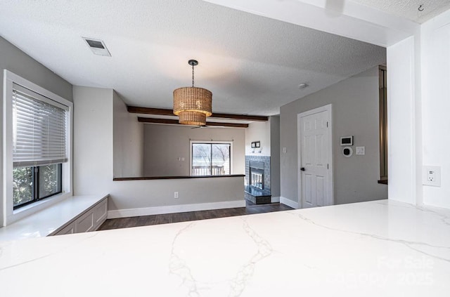 interior space featuring a glass covered fireplace, wood finished floors, baseboards, and a textured ceiling