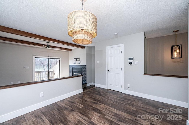 interior space featuring a fireplace, beam ceiling, wood finished floors, and a textured ceiling