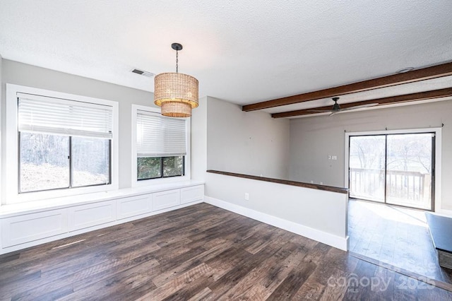 unfurnished room featuring baseboards, beam ceiling, ceiling fan with notable chandelier, dark wood-style floors, and a textured ceiling