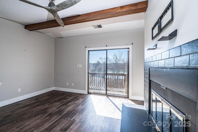 unfurnished living room featuring beam ceiling, a fireplace with flush hearth, visible vents, and dark wood-style flooring