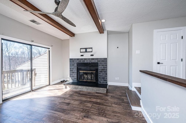 living area with beamed ceiling, dark wood-type flooring, visible vents, and ceiling fan