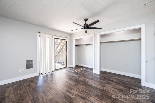 unfurnished bedroom featuring a textured ceiling, two closets, baseboards, and wood finished floors