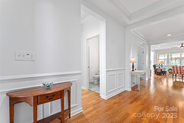 corridor with crown molding and light wood finished floors