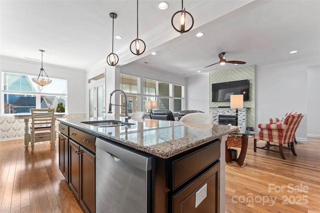 kitchen featuring light stone countertops, ornamental molding, a sink, light wood-style floors, and dishwasher