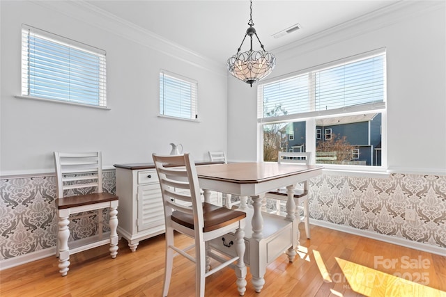 dining area with a notable chandelier, plenty of natural light, light wood-type flooring, and ornamental molding