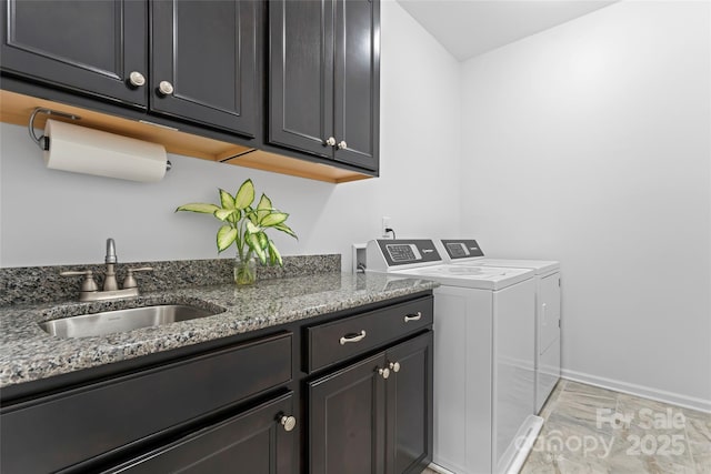 laundry area with a sink, baseboards, cabinet space, and independent washer and dryer