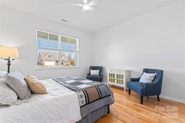 bedroom featuring visible vents, baseboards, wood finished floors, and a ceiling fan