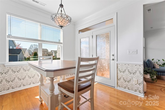 dining area with visible vents, a notable chandelier, crown molding, and light wood finished floors