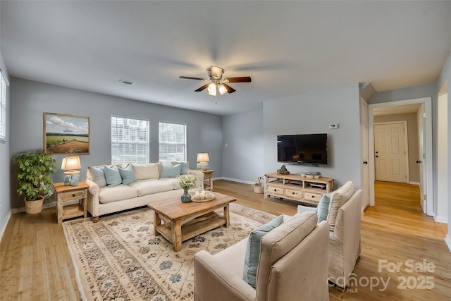 living room featuring visible vents, light wood-style flooring, baseboards, and a ceiling fan