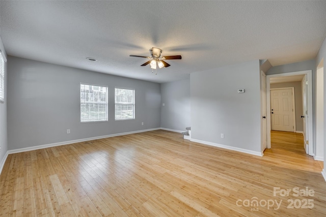 spare room featuring baseboards, visible vents, light wood finished floors, and ceiling fan