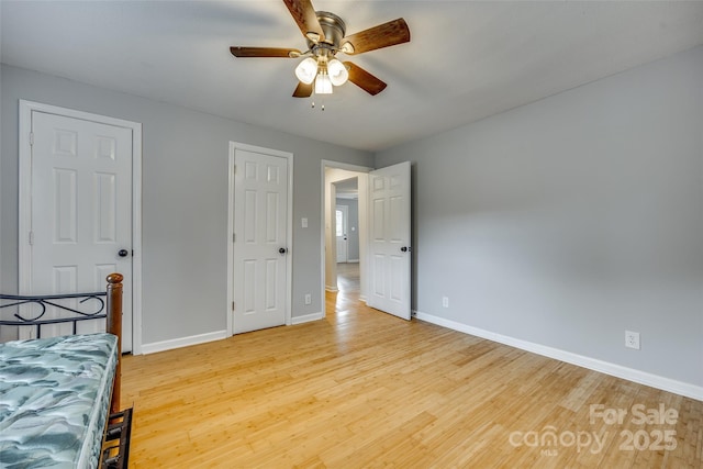 unfurnished bedroom featuring a ceiling fan, light wood-style floors, and baseboards