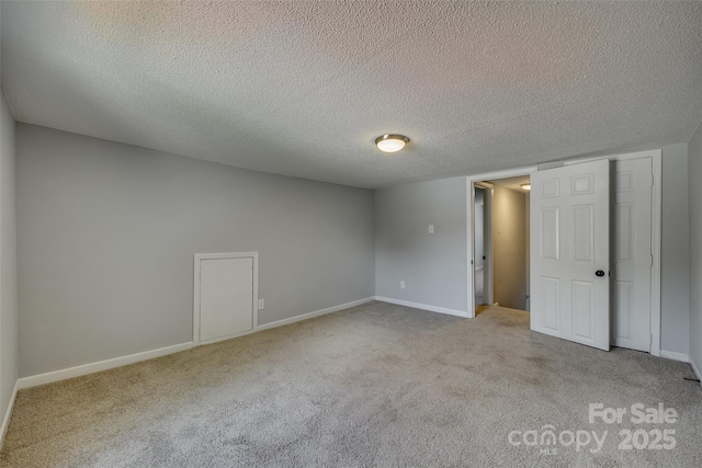 unfurnished bedroom with a textured ceiling, baseboards, and carpet