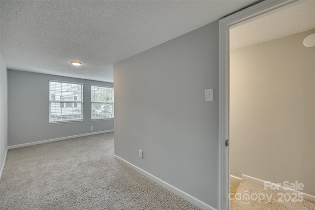 unfurnished room with baseboards, a textured ceiling, and carpet