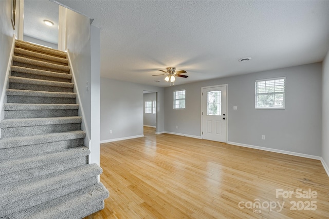 foyer entrance with visible vents, ceiling fan, stairs, and light wood-style floors