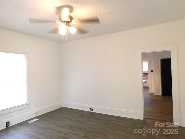 spare room featuring dark wood finished floors, baseboards, visible vents, and ceiling fan