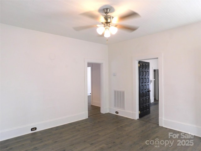 empty room featuring visible vents, baseboards, dark wood-type flooring, and ceiling fan