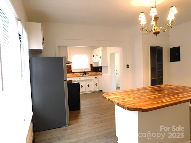 kitchen featuring wooden counters, freestanding refrigerator, a sink, light wood-style floors, and white cabinetry