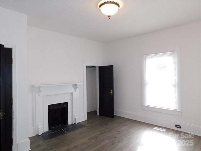 unfurnished living room featuring a fireplace, visible vents, wood finished floors, and baseboards