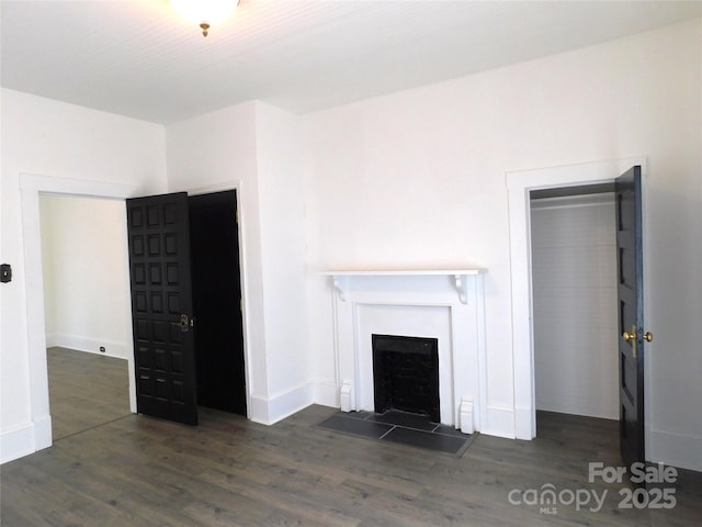 unfurnished living room with wood finished floors, a fireplace, and baseboards