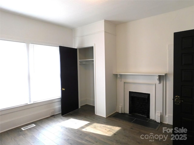 unfurnished living room with a fireplace, wood finished floors, and visible vents