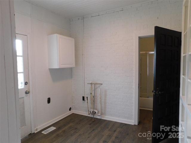 washroom with visible vents, brick wall, baseboards, dark wood finished floors, and cabinet space