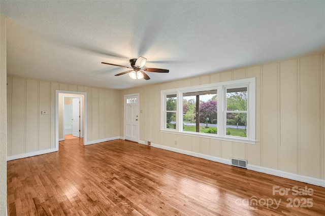 110 Maplewood Knoll Dr, East Flat Rock, NC 28726 - unfurnished room featuring a ceiling fan, visible vents, a decorative wall, baseboards, and wood finished floors