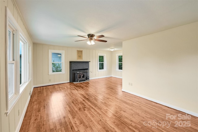 110 Maplewood Knoll Dr, East Flat Rock, NC 28726 - unfurnished living room featuring a wood stove, a ceiling fan, baseboards, and light wood-type flooring