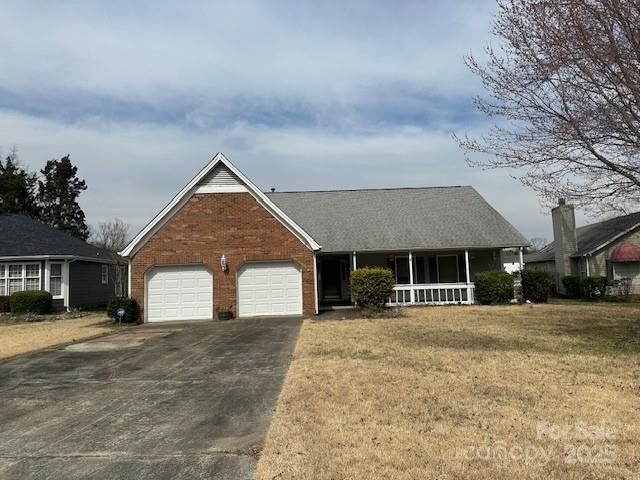 view of front facade featuring brick siding, a front lawn, a porch, concrete driveway, and a garage