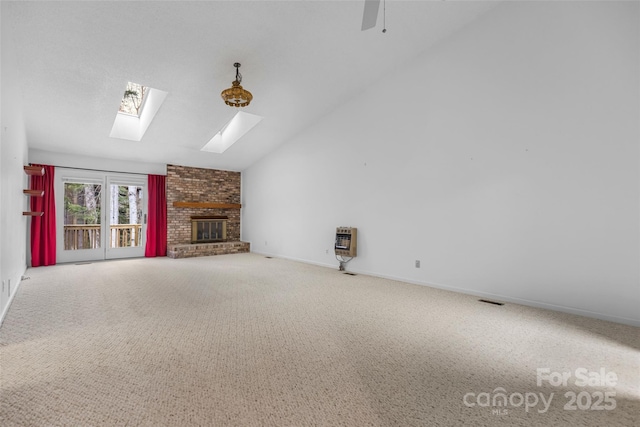 unfurnished living room featuring heating unit, baseboards, carpet floors, lofted ceiling with skylight, and a brick fireplace