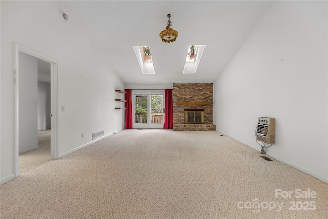 unfurnished living room featuring visible vents, heating unit, carpet floors, a skylight, and a fireplace