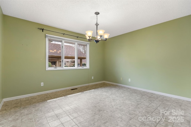 empty room with a textured ceiling, visible vents, baseboards, and a chandelier