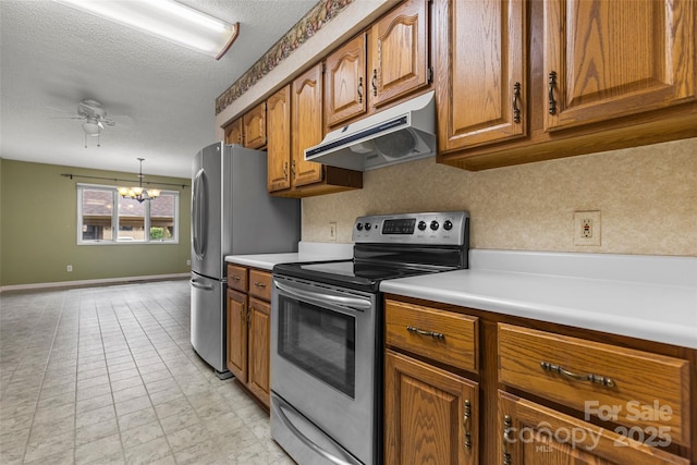 kitchen featuring ceiling fan with notable chandelier, under cabinet range hood, a textured ceiling, stainless steel appliances, and brown cabinetry