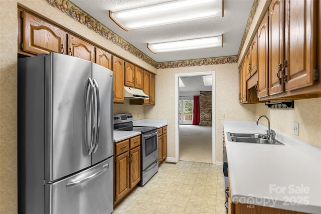 kitchen with under cabinet range hood, light floors, stainless steel appliances, a textured ceiling, and a sink