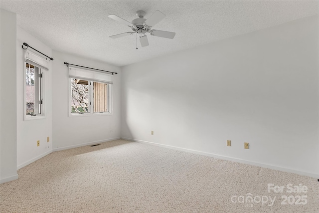 spare room with visible vents, a textured ceiling, carpet floors, baseboards, and ceiling fan