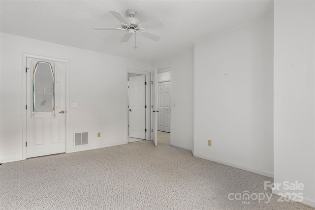 carpeted spare room featuring visible vents, baseboards, and ceiling fan