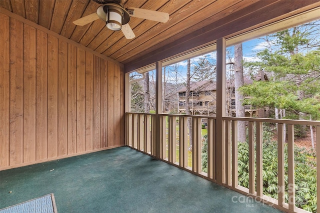 unfurnished sunroom with wood ceiling and a ceiling fan