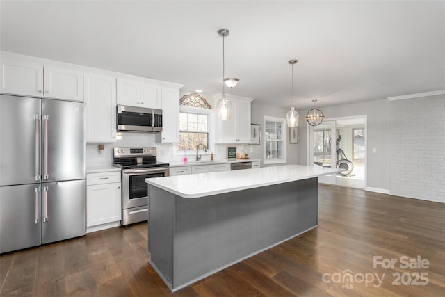 kitchen with a sink, light countertops, appliances with stainless steel finishes, white cabinetry, and dark wood-style flooring