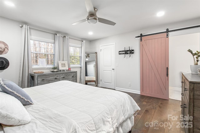 bedroom featuring a barn door, recessed lighting, dark wood-style floors, and baseboards