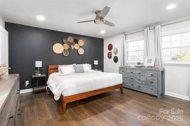 bedroom with an accent wall, baseboards, and dark wood-style flooring