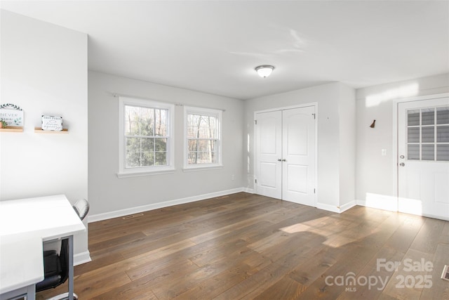 unfurnished bedroom with baseboards and dark wood-style floors