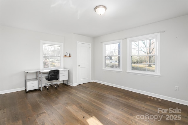 unfurnished office featuring visible vents, baseboards, and dark wood-style floors